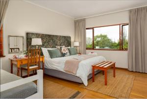 开普敦Valley Heights Guest House and B & B的一间卧室配有一张大床、一张书桌和一个窗户。