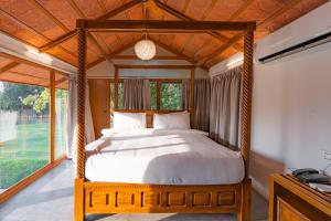 海得拉巴Brown Town Resort & Spa的一间卧室设有一张带大窗户的天蓬床