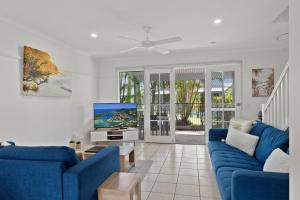 努萨维尔可可湾度假村的客厅配有蓝色的沙发和电视