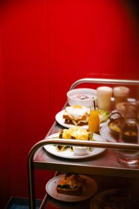 维也纳Hotel Babula am Augarten的红色墙上有盘子的桌子