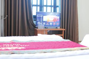 清化Biển Hải Tiến - Nhà nghỉ Ngân Khánh的一间卧室配有一张床和一张桌子上的电视