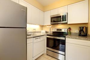 卡哈纳Paki Maui 313的厨房配有白色橱柜和不锈钢冰箱