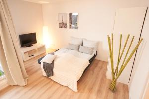 不莱梅Gemütliches und helles Studio Apartment mit Balkon, Badewanne, WLAN, Parkplatz的白色的客房配有床和电视。