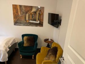 FaxeLedvogterhuset B&B的一间卧室配有两把椅子、一台电视和一张床
