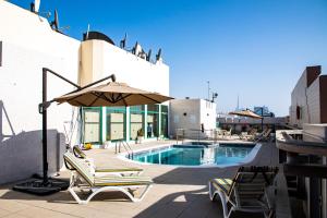 迪拜West Zone Pearl Hotel Apartment的游泳池旁的天井配有椅子和遮阳伞。
