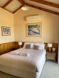 旺加拉塔瓦比农家乐的一间卧室配有一张带两盏灯的大型白色床。