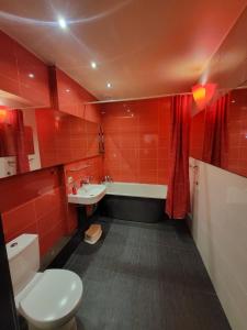 尤尔马拉Meza House Apartment的红色的浴室设有卫生间、水槽和浴缸。