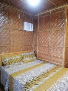 圣胡安Almare Guest House Siquijor的卧室配有木墙内的一张床