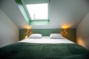 亨克City Housing Genk的一间卧室配有带两个枕头的床和窗户