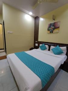 孟买Hotel Amber-colaba的卧室配有带蓝色枕头的大型白色床