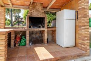 维罗维-德欧纳Casa rural con piscina, barbacoa, WIFI的室外厨房设有砖砌壁炉和冰箱。