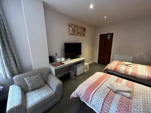 爱丁堡阿陈瑞轩宾馆的客房设有两张床、一把椅子和电视。