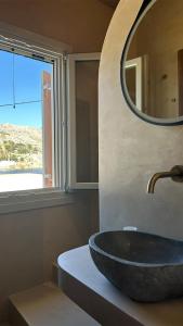 锡米Amalthea Luxury Suites的一间带石制水槽和镜子的浴室