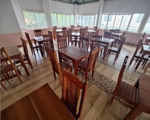 提喀迪T Homes Thekkady的餐厅设有木桌、椅子和窗户。