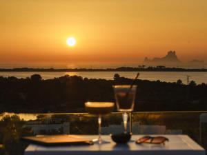 埃斯普霍斯Five Flowers Hotel & Spa Formentera的一张桌子,喝一杯,欣赏日落美景