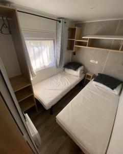 圣让-德蒙Superbe Mobil home 6-8 personnes (57)的小房间设有两张床和窗户
