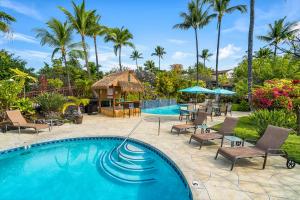 科纳Keauhou Resort 113的一个带椅子和凉亭的游泳池,并种植了棕榈树