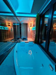 斯科普里Smart Luxury Penthouse Suites - Private Sauna, Hot-Tub, Home Cinema at the best Location in Skopje的蓝色灯的中间的浴缸