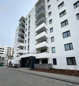 托伦Apartament Nr 50, 2 sypialnie, wygodny parking podziemny的白色的建筑,旁边设有阳台