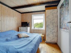 约灵Holiday Home Stella - 700m from the sea in NW Jutland by Interhome的一间卧室设有蓝色的床和窗户。