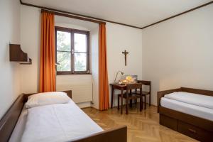 弗思Gästehaus Benediktinerstift Göttweig - Bed & Breakfast Monastery的客房设有两张床、一张桌子和一扇窗户。