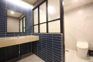 釜山Hotel Prima Busan的蓝色瓷砖浴室设有水槽和卫生间
