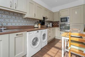 WhittingehameStylish country home near East Linton and Edinburgh的厨房配有白色橱柜、洗衣机和烘干机
