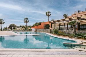 夏卡Mangia's Torre Del Barone Resort的棕榈树度假村的游泳池以及大楼