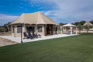 ParrillasEl Toril Glamping Experience的田野上带桌椅的帐篷