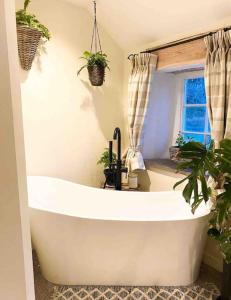 阿利士Charming, rustic & well equipped garden cottage的浴室设有白色浴缸,种植了植物。