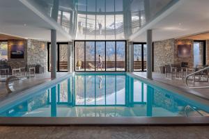 里雾诗Les Granges d'en Haut - Chamonix Les Houches的一座大型游泳池,位于一座带窗户的建筑内