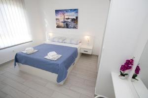 普罗马尼亚Luxury Apartment Luka的一间白色的小卧室,配有蓝色的床和鲜花