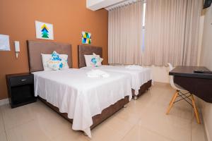 塔拉波托Tropical City的一间卧室配有一张带白色床单的床和一张书桌。