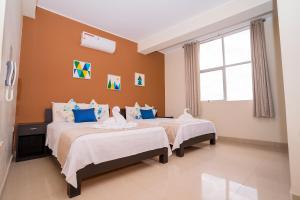塔拉波托Tropical City的橙色墙壁客房的两张床