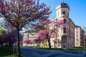 都灵[Porta Nuova - Alpitour] Free Parking & Netflix的一座有塔楼和紫色花卉的树的建筑