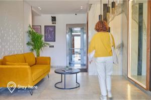 拉巴特Stayhere Rabat - Hay Riad - Sophisticated Residence的一位女士在客厅里走,客厅里摆放着黄色的沙发