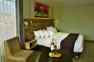 阿雷基帕Terramística Arequipa - Monasterio的酒店客房,配有一张床和一张桌子,并备有一瓶葡萄酒
