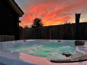 BawdeswellSaving Grace with private hot tub的按摩浴缸,背面是日落