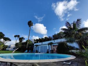 Rabo de PeixeQuinta Minuvida的棕榈树屋前的游泳池