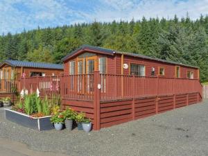 格伦德文Poppy Lodge Glendevon Scotland的大型小木屋设有围栏和鲜花