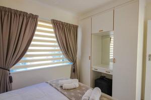 逊邱伦The Lemon Tree Oasis - Solar的一间卧室配有床和带毛巾的窗户。