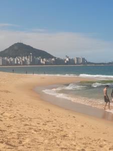 维拉维尔哈Espaçosa kitnet em itapua 10 min da praia.的几个在海滩上散步的人