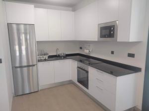 SerantesAnam Cara House的厨房配有白色橱柜和不锈钢冰箱