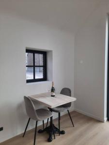 KruisemKomo Hill Stays - guestroom Komo Cosy的一张带两把椅子的白色桌子和一瓶葡萄酒