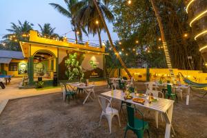 安君纳Whoopers Hostel Anjuna, Goa的大楼前设有桌椅的餐厅