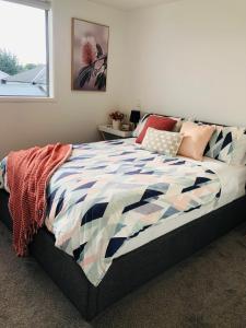 基督城Perfect modern Townhouse CBD Christchurch的一间卧室配有一张带五颜六色棉被的床