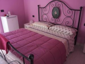 阿夸维瓦皮切纳B&B Il Giardino Mediterraneo的粉红色的卧室,配有一张带紫色棉被的床