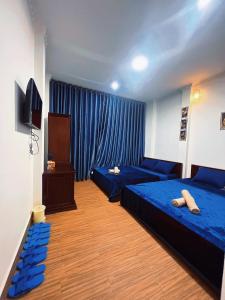 芹苴Nhan Tay Hostel的一间卧室配有2张蓝色的床和电视