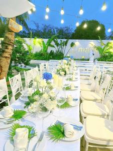 Trà VinhMalis Homestay的白色长桌,带白色椅子和鲜花
