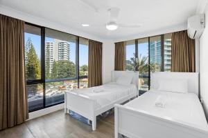 黄金海岸创世纪公寓酒店的带大窗户的客房内的两张床